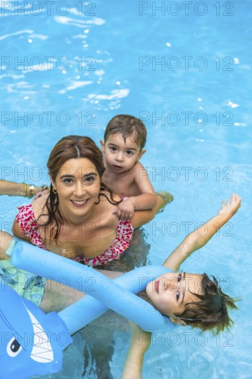 Happy family enjoying sunny summer vacation in the pool, playing joyfully with inflatable toys and creating lasting memories together