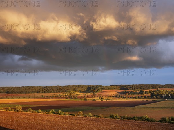 Field landscape in autumn, ploughed fields under dark storm clouds with rainbow in the evening light, Freyburg, Saxony-Anhalt, Germany