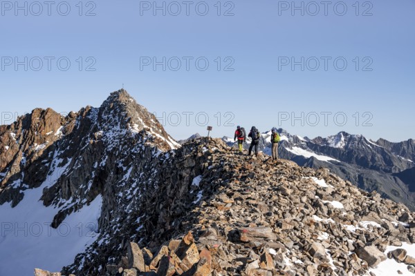 Mountaineer on a ridge, in the background summit Wilder Freiger with summit cross, Stubai Alps, South Tyrol, Italy
