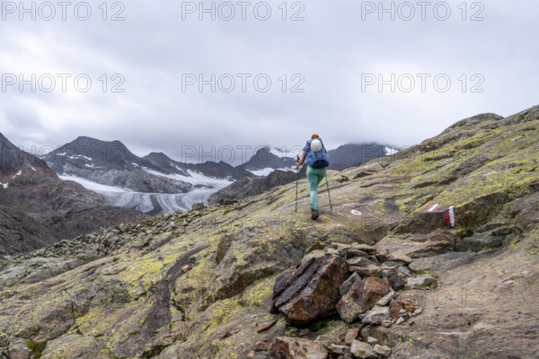 Mountaineer on hiking trail in high mountain landscape, view of glacier tongue of the Übeltalferner, Stubai Alps, South Tyrol, Italy