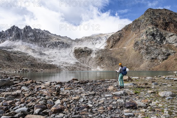 Mountaineer in front of mountain landscape with limestone rocks between granite mountains, mountain lake Hinterer Senner Egetsee and mountain peak of the Moarer Weißen, Seven Lakes Hike, Stubai Alps, near Ridnaun, South Tyrol, Italy