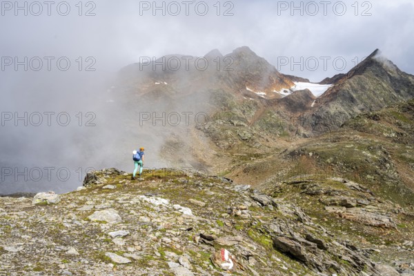 Mountaineer on a hiking trail, cloudy mountain landscape, Egetenjoch, Seven Lakes Hike, Stubai Alps, near Ridnaun, South Tyrol, Italy