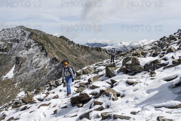 Two female mountaineers in boulder terrain with fresh snow in summer, ascent to the summit Böses Weibl, Wiener Höhenweg, Schober group, Hohe Tauern National Park, Carinthia, Austria