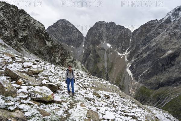 Mountaineer on steep rocky mountain landscape with fresh snow in summer, behind mountain peaks Großer Friedrichskopf and Georgskopf, ascent to Hornscharte, Schober group, Hohe Tauern National Park, Carinthia, Austria