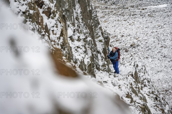 Mountaineer on a rope-secured path in a steep, rocky mountain landscape with fresh snow in summer, ascent to the Hornscharte, Schober Group, Hohe Tauern National Park, Carinthia, Austria