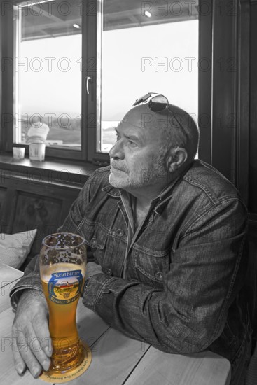 Elderly gentleman with sunglasses and wheat beer in a pub, black and white, Bavaria, Germany