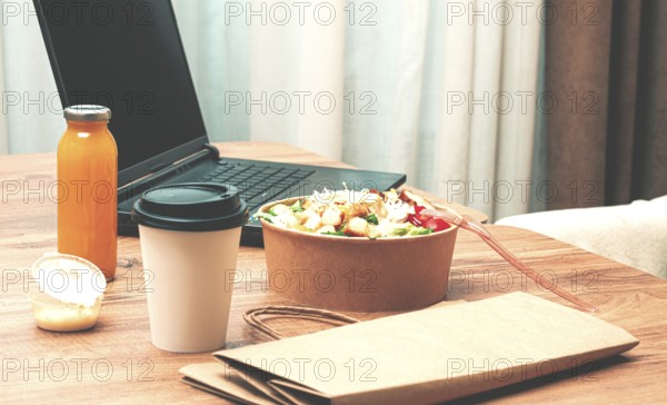 Work at home on a laptop, there is food on the table, salad, coffee and juice, delivery, there are no people