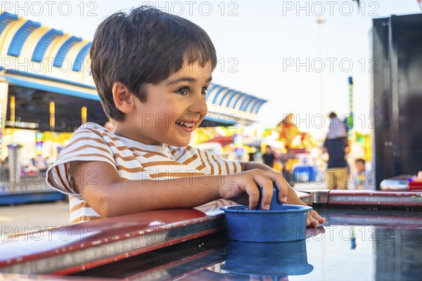 Smiling young boy playing a game at an amusement park, surrounded by colorful attractions and bright lights, capturing the essence of childhood fun