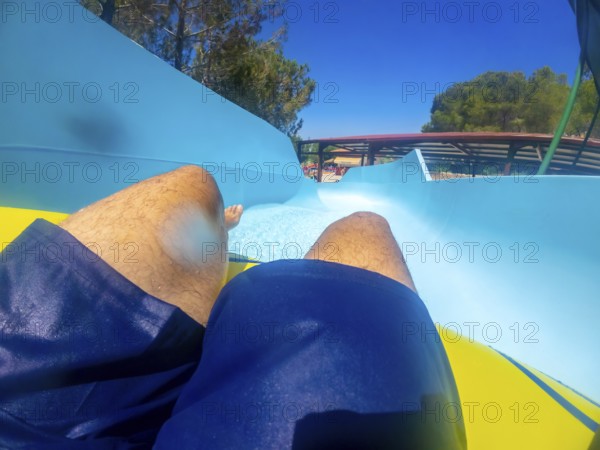 Point of view of a man sliding down a thrilling waterslide at an aquatic park, enjoying summer holidays filled with fun and excitement
