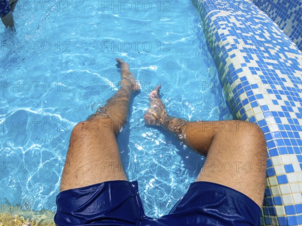 Man relaxing in a blue swimming pool, enjoying the refreshing water on a sunny summer day, embracing a carefree vacation vibe