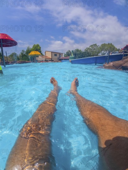 Pov shot of a man relaxing in a swimming pool at a water park, enjoying the summer sun and the refreshing water