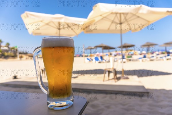 Cold beer glass sits on a table at a beach resort, offering a refreshing escape under the summer sun