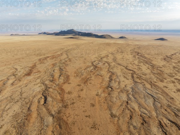 Dried-up river beds and isolated mountain ridges at the edge of the Namib Desert. Aerial view. Drone shot. Namibia