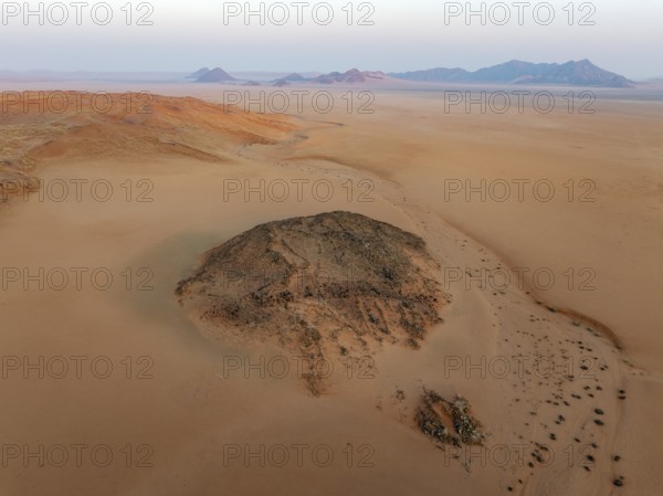 Arid plains, sand dunes and bare mountain ridges at the edge of the Namib Desert. Aerial view. Drone shot. Namibia