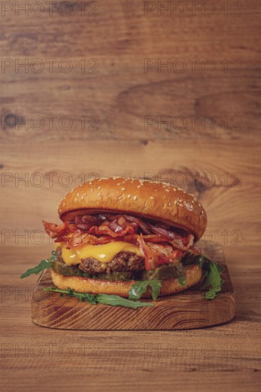 Burger with beef and bacon, with arugula and caramelized onions, pickles, sauce, homemade, no people