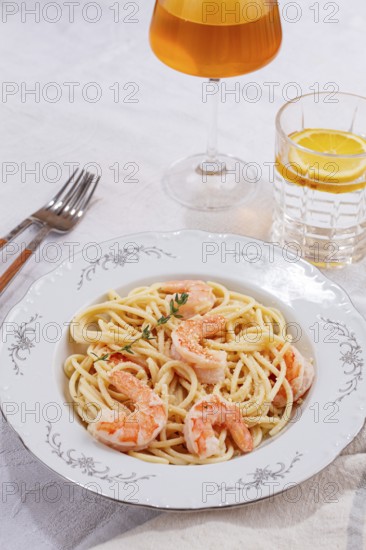 Pasta with shrimp and thyme, served on a white plate, with a glass of white wine, the table is set, Gourmet dinner, on a linen tablecloth, no people