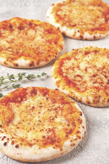 Four pizzetta Margaritas, on a light grey surface, top view