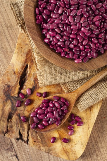 Red beans, laid out in a wooden bowl, on a chopping board, rustic style, covered with burlap, top view, close-up