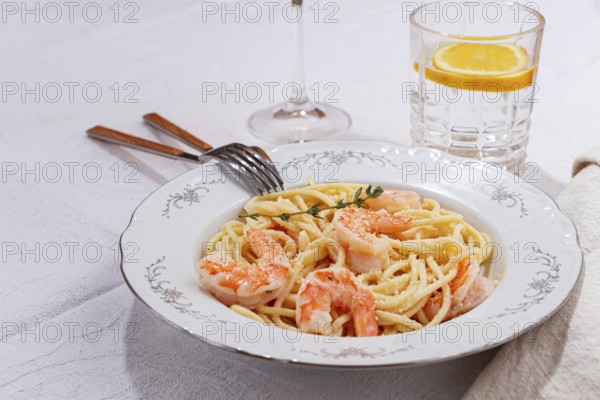 Pasta with shrimp and thyme, served on a white plate, with a glass of white wine, the table is set, Gourmet dinner, on a linen tablecloth, no people