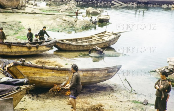 Cleaning the hull of a boat with flames from a small fire in a process known as breaming, Castle Peak, New Territories, Hong Kong, Asia, 1964