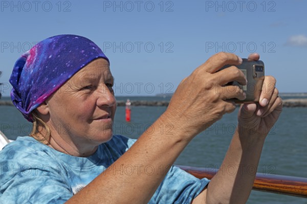 Elderly woman taking photos with smartphone, Warnemünde, Rostock, Mecklenburg-Western Pomerania, Germany