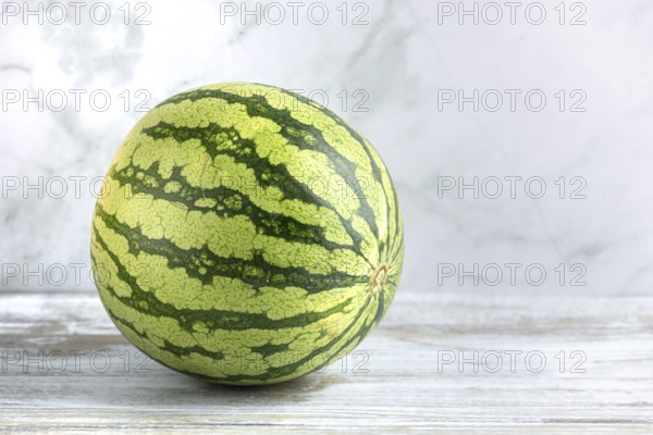 Watermelon on a wooden surface against a marbled background