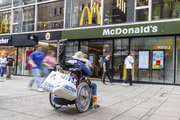 A man in a wheelchair in the Königstraße pedestrian zone in front of a branch of the McDonald's fast food chain. Stuttgart, Baden-Württemberg, Germany