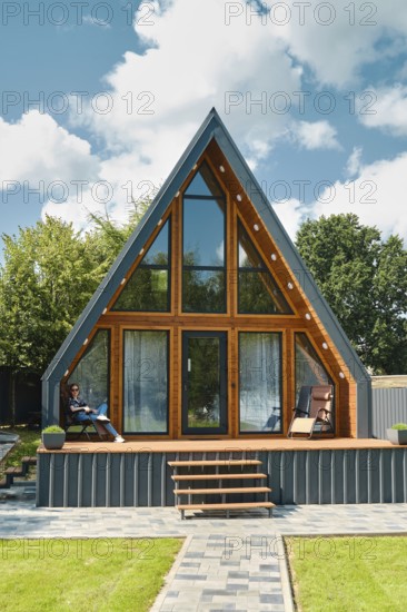 Young woman sitting on a folding chair on the terrace of a tiny house