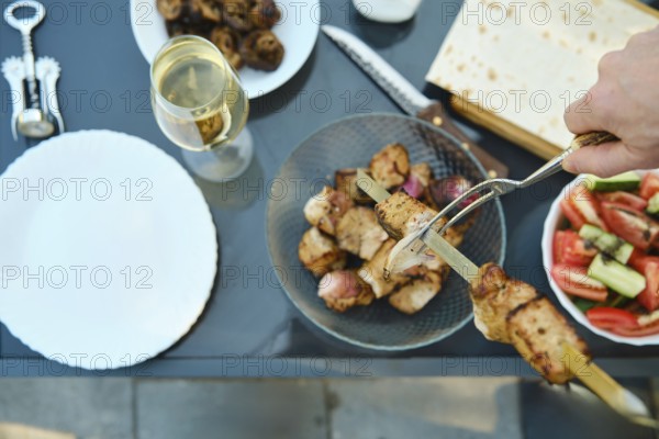 Overhead view of removing kebab from skewer with a fork