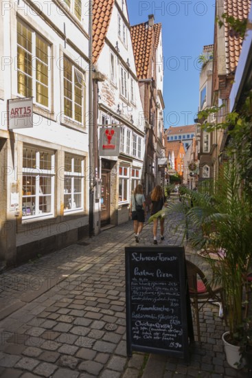 Renovated Schnoor neighbourhood with small shops, galleries, restaurants, cafés and residential buildings, Gängeviertel in the old town, former fishermen's and boatmen's settlement, narrow alleyways, pedestrian zone, numerous listed buildings, classicist, historicist, baroque and renaissance architecture, flower pots, sales stands, tourist attraction, destination, pleasure, Hanseatic city of Bremen, Germany