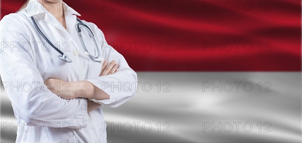 Doctor with crossed arms on Monaco flag. Monaco health and care concept. Female doctor on Monaco flag
