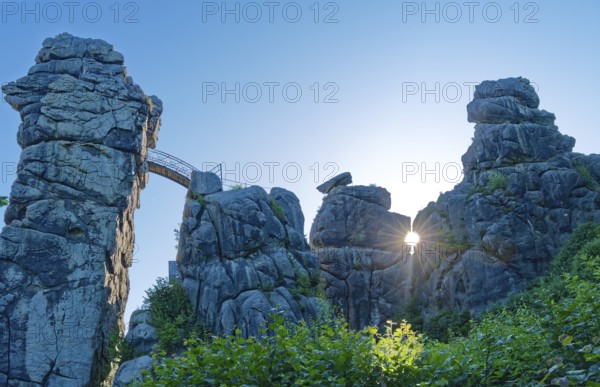 The morning sun shines through an opening in the Externsteine. The Externsteine, a sandstone rock formation around 40 metres high in the Teutoburg Forest, are a natural sight and are a protected natural and cultural monument. They are regarded as a place of power and are considered to have special cultural and historical significance. Horn-Meinberg, North Rhine-Westphalia, Germany