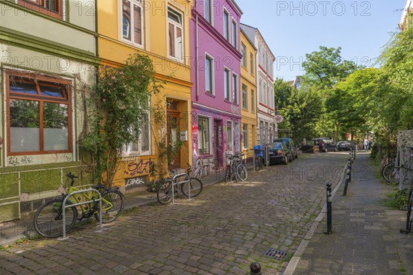 Colourful residential street in the Ostertor quarter a popular residential area, eastern suburb, bicycles, bicycle stands, trees, Wilhelminian style buildings, cobblestones, traffic-calmed, facades, Bremen, Germany