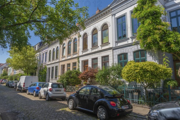 Residential street in the Ostertor neighbourhood a popular residential area, eastern suburb, Wilhelminian style building, traffic-calmed, facades, cars, parking, cobblestones, trees, sunshine, Bremen, Germany
