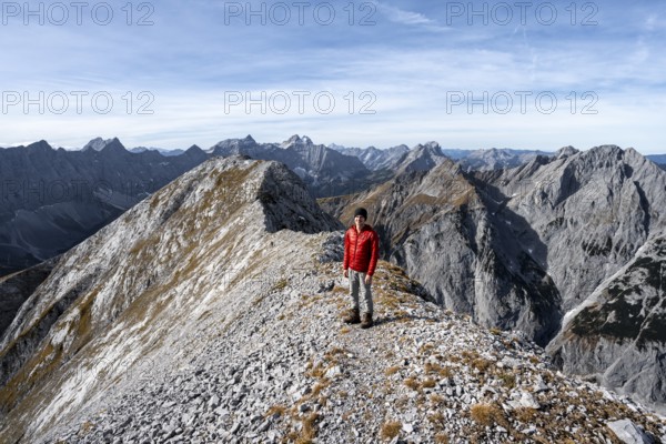 Mountain panorama, mountaineer on the ridge of the Gamsjoch, transition to the main summit of the Gamsjoch, behind western summit with summit cross, behind mountain ridge of the Hinterautal-Vomper chain, in autumn, RiÃŸtal in the Eng, Karwendel, Tyrol, Austria