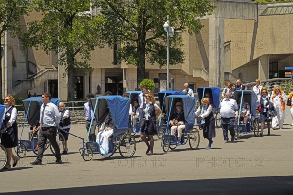 Elderly pilgrims are driven by helpers to the Marian pilgrimage site of Lourdes, Pyrenees, France