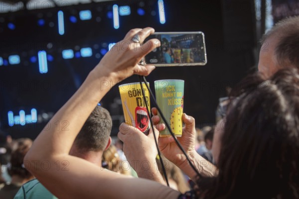 Fans photograph their mugs with the words Gönn' Dir und Ick könn Dir kÃ¼ssen on them at the Berliner Rundfunk 91.4 Open Air at the Berlin ParkbÃ¼hne Wuhlheide on 5 July 2025