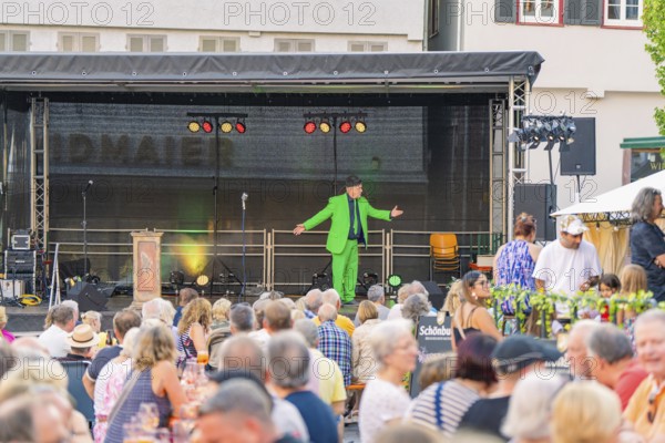 An entertainer on a stage entertains a large audience at an evening event, 950 years Weil der Stadt ceremony, Böblingen district, Germany
