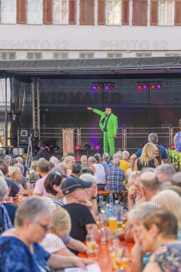 A man in a green suit stands on a stage and speaks to a large crowd, 950 years Weil der Stadt ceremony, Böblingen district, Germany
