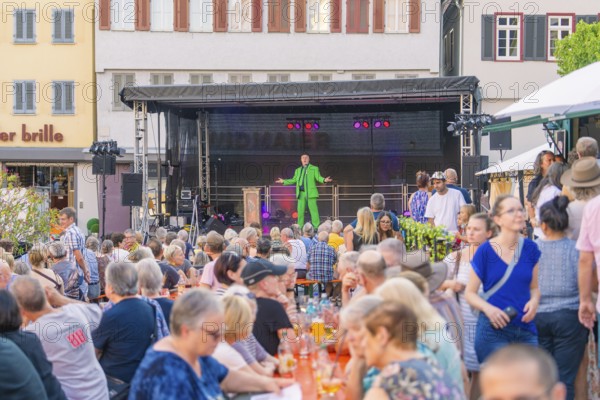 A man on stage entertains a large audience at an outdoor event, 950 years Weil der Stadt ceremony, Böblingen district, Germany
