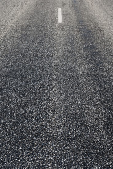 Rustige asfaltweg zonder voertuigen, met een enkele witte middenlijn zichtbaar. De weg strekt zich uit in de verte onder een heldere lucht. Bas Rhin, Alsace, France