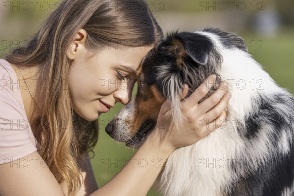 Woman holding Australian Shepherd dog with foreheads touching. Tender moment of emotional connection between human and animal. Generative ai, AI generated