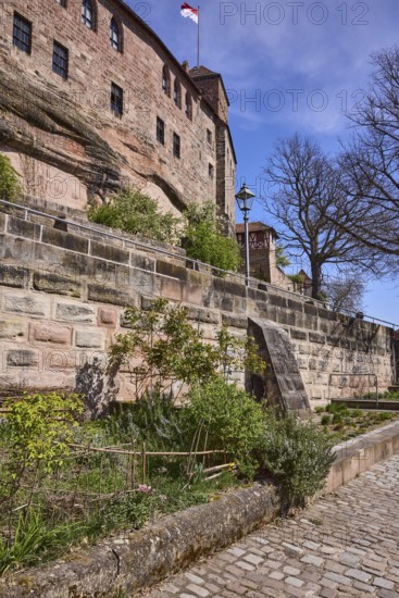 Imperial castle, old town, historic buildings, castle wall, flag, sandstone wall, footpath, cobblestones, trees, garden, blue sky, cirrostratus clouds, Am Ã–lberg, Nuremberg, Middle Franconia, independent city, Bavaria, Germany