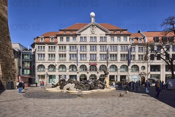 NEhekarussell, sculptor JÃ¼rgen Weber, marriage fountain, Hans Sachs fountain, fountain with bronze sculptures, fashion shop, Rudolf Wöhrl SE, pedestrian zone, historical building, pedestrian as secondary motif, blue sky, cloudless, Ludwigsplatz, Ã¼rnberg, Middle Franconia, independent city, Bavaria, Germany