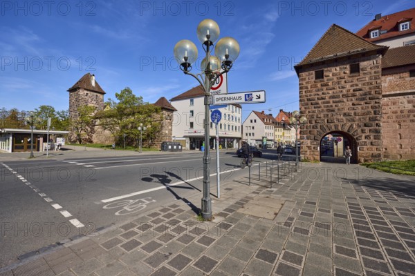 City fortification, city wall, city gate, defence defence tower, lantern, general architecture, pavement made of concrete paving stones, cycle path, trees, signpost to the opera house, blue sky, cirrostratus clouds, FÃ¤rbertor, FÃ¤rbertorstraÃŸe, Nuremberg, Middle Franconia, independent city, Bavaria, Germany