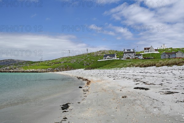 Quiet sandy beach with neighbouring houses under a slightly cloudy sky, Outer Hebrides, Eriksay, Scotland, United Kingdom