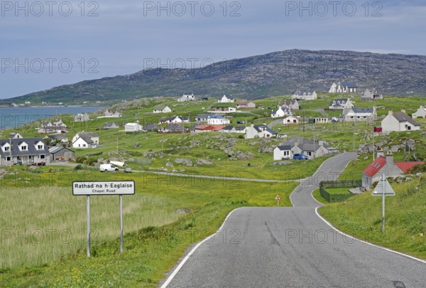 Small village in a hilly landscape with white houses and a main road, Outer Hebrides, Eriksay, Scotland, United Kingdom