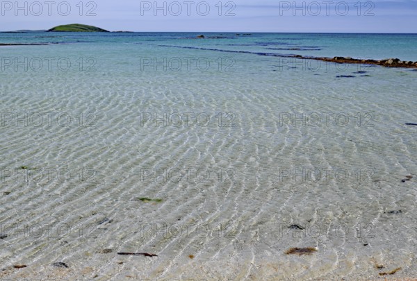 Clear bright blue beach with gentle waves under a cloudless sky, Outer Hebrides, Eriksay, Scotland, United Kingdom