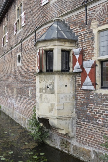 Medieval bay window on a brick wall with red shutters and moat, Raesfeld Castle, MÃ¼nsterland, North Rhine-Westphalia, Germany