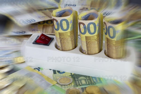 Symbolic image of electricity costs: multiple socket outlet with euro banknotes and euro coins